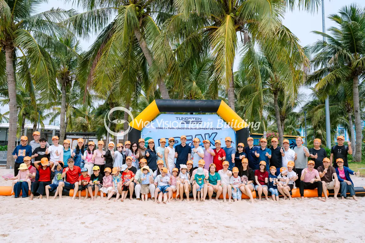 Đoàn doanh nghiệp tham gia team building trên bãi biển với backdrop và khu vực chơi rõ ràng