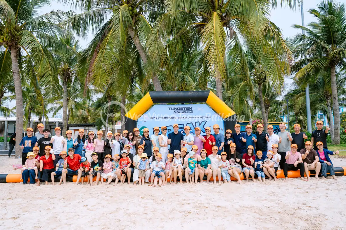 Đoàn công ty chụp ảnh trong khu team building biển với nón nhận diện đồng bộ