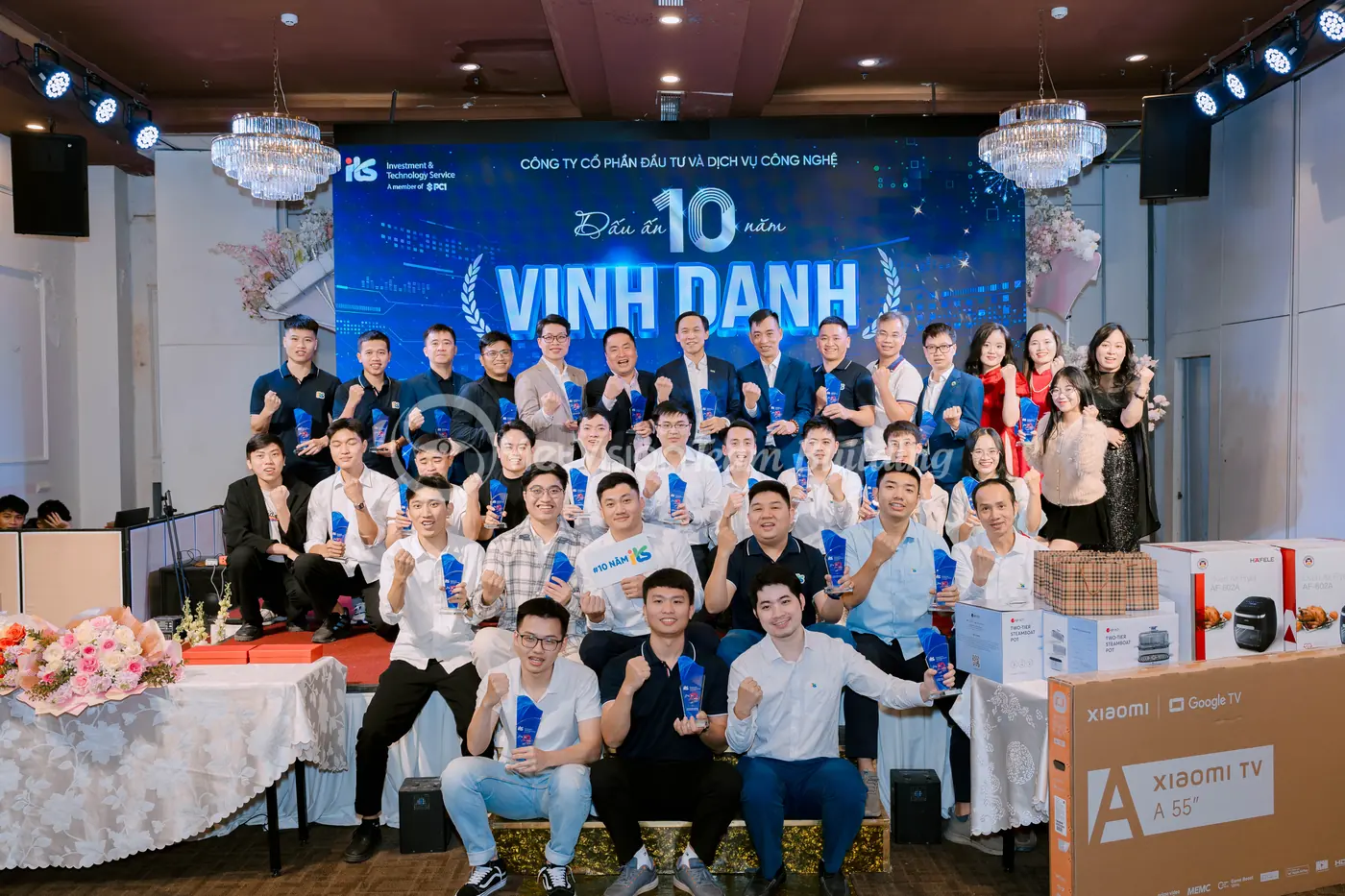 Ảnh tập thể công ty trước backdrop sự kiện team building và gala