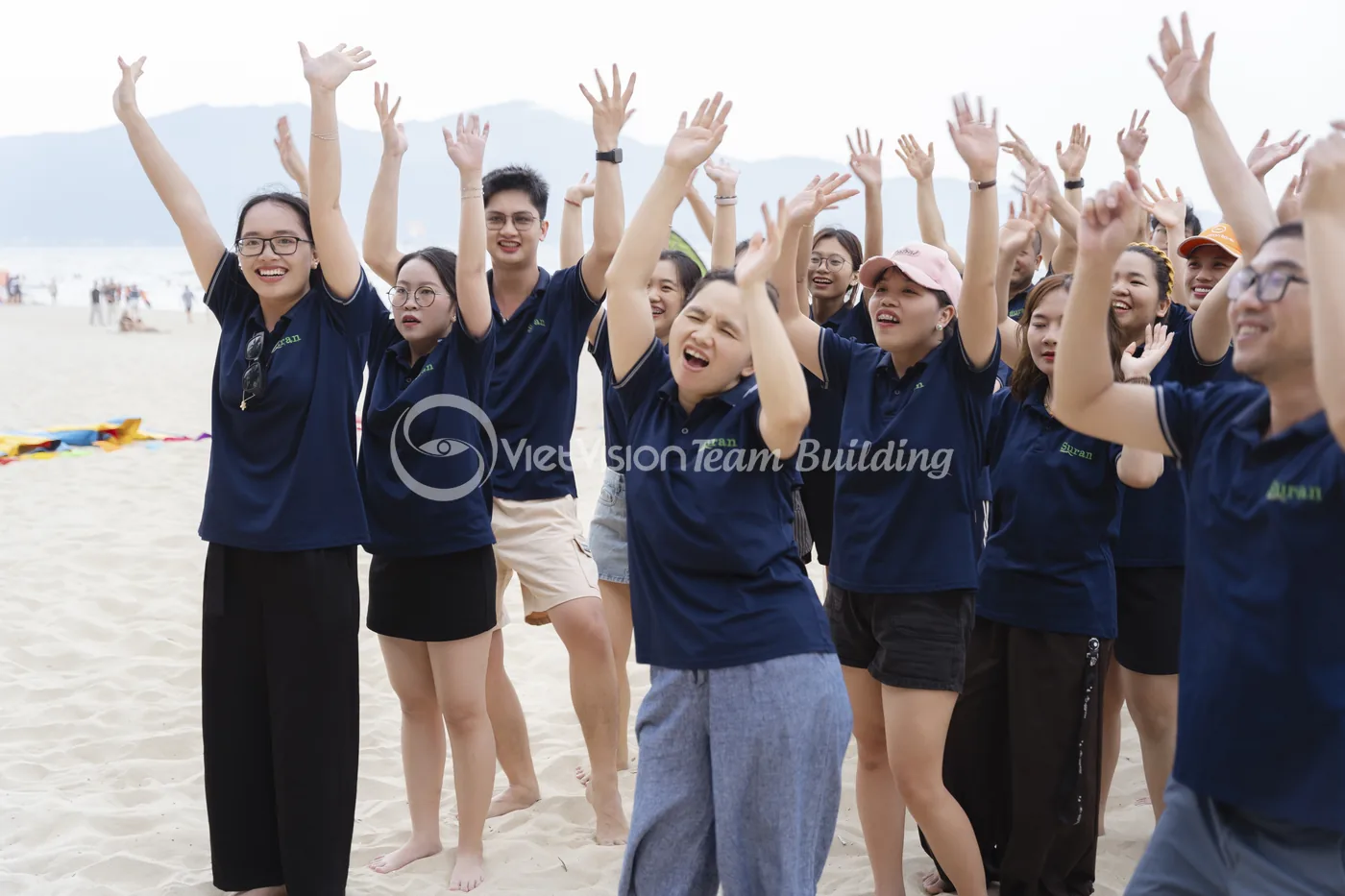 Nhóm nhân viên giơ tay hào hứng sau khi tham gia team building cùng đồng đội