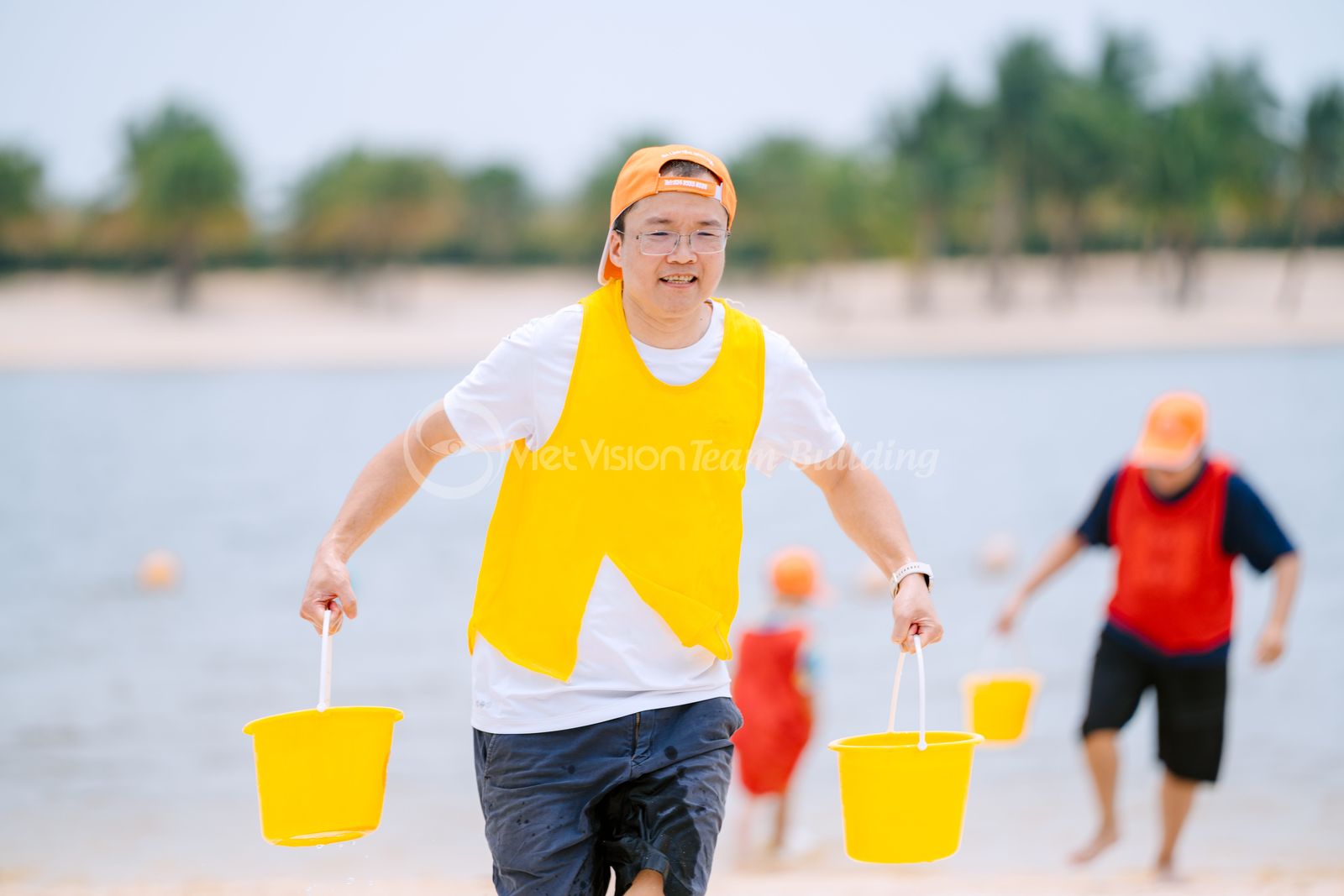 Người chơi di chuyển trên cát gần mép nước trong chương trình team building bãi biển