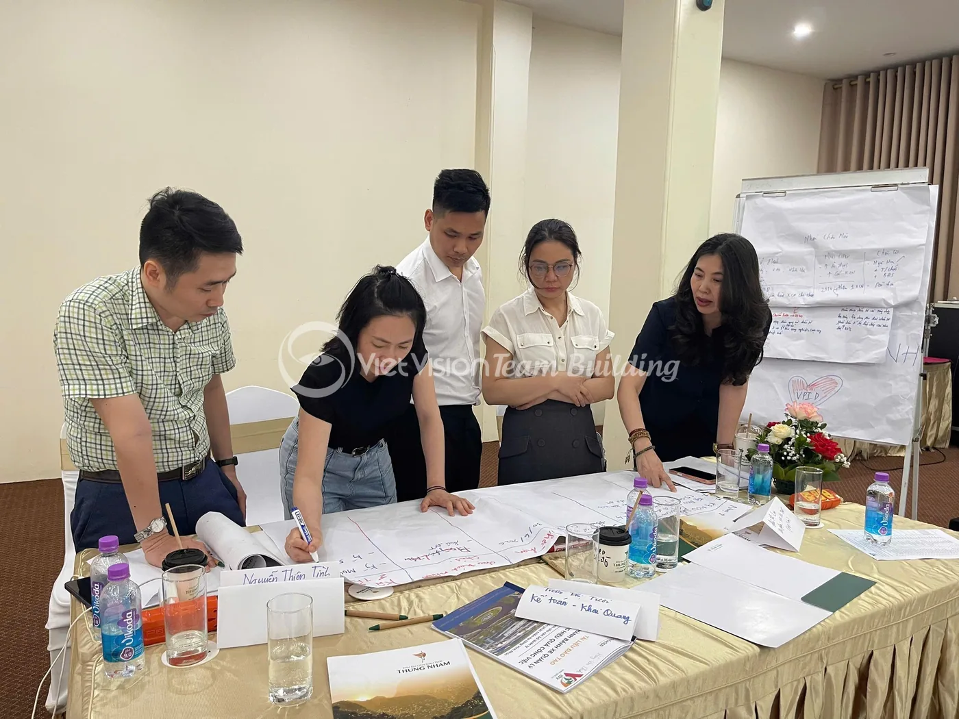 Nhóm nhân sự cùng xem tài liệu và thảo luận trong buổi onboarding kết hợp team building