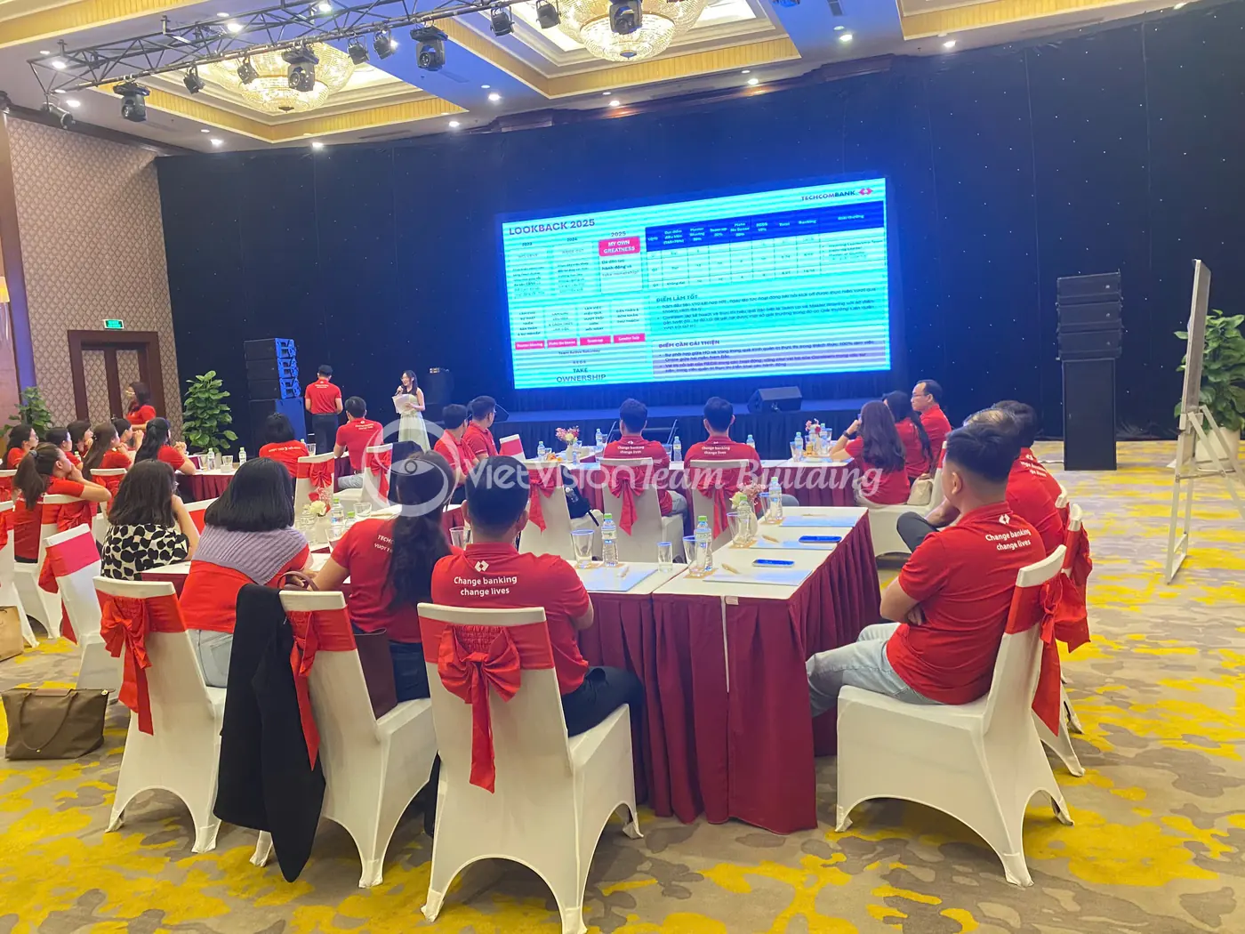Người tham gia ngồi theo bàn nhóm trong phần tổng kết sau hoạt động team building