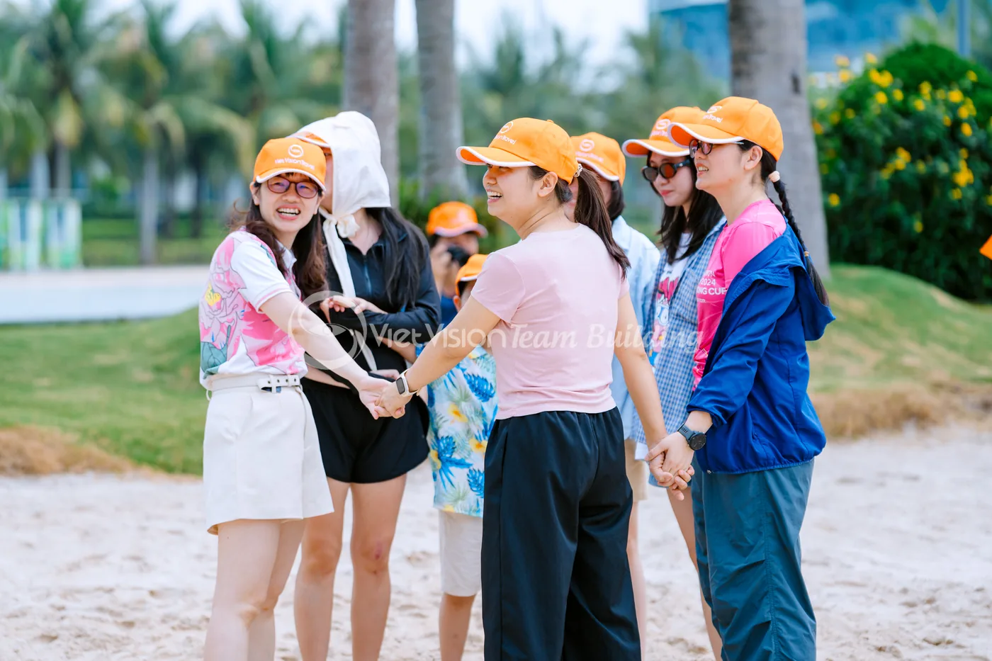Nhóm nhân viên nắm tay theo vòng nhỏ trong hoạt động team building ngoài trời