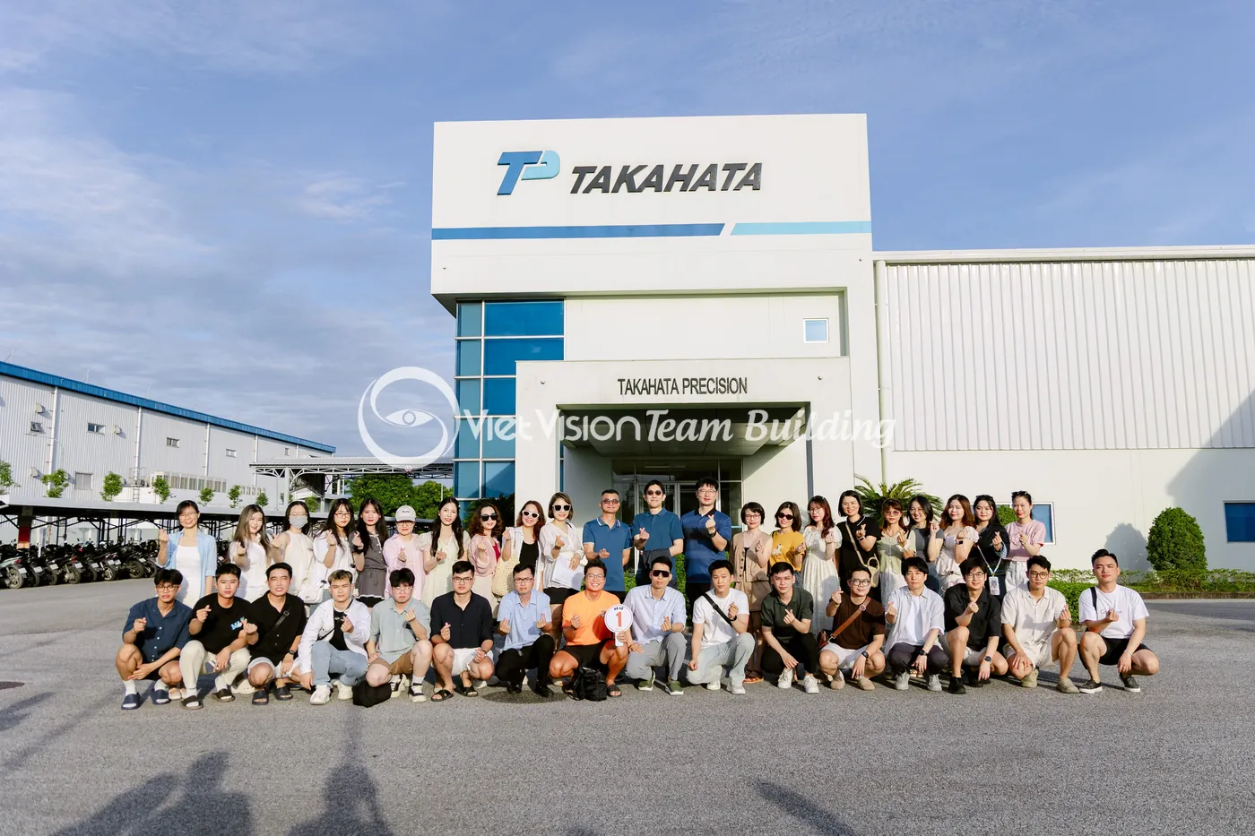 Đoàn công ty sản xuất chụp ảnh tại cổng nhà máy trước chuyến team building Hạ Long