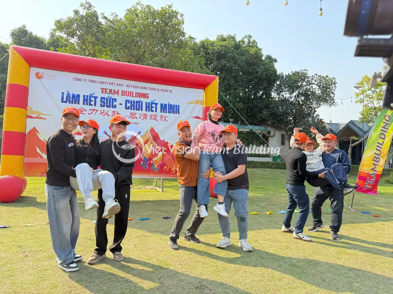 Nhóm người chơi phối hợp trong thử thách team building trước backdrop