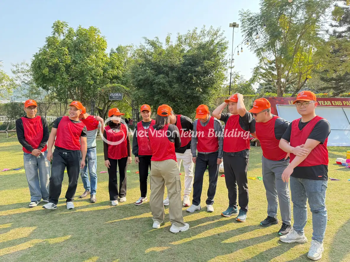 Đội chơi mặc áo lưới đỏ đứng chờ hướng dẫn trước thử thách team building