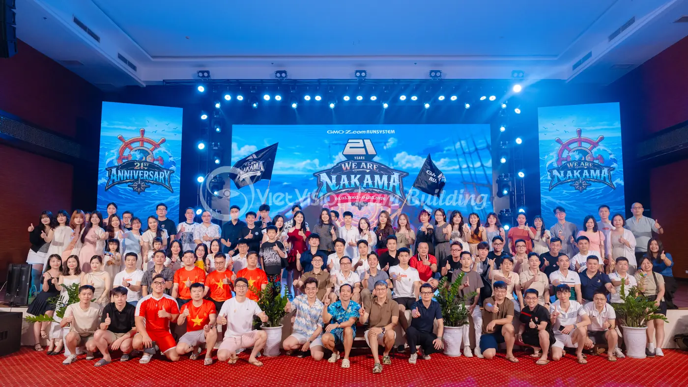 Đội ngũ chụp ảnh trước backdrop có tên chủ đề team building