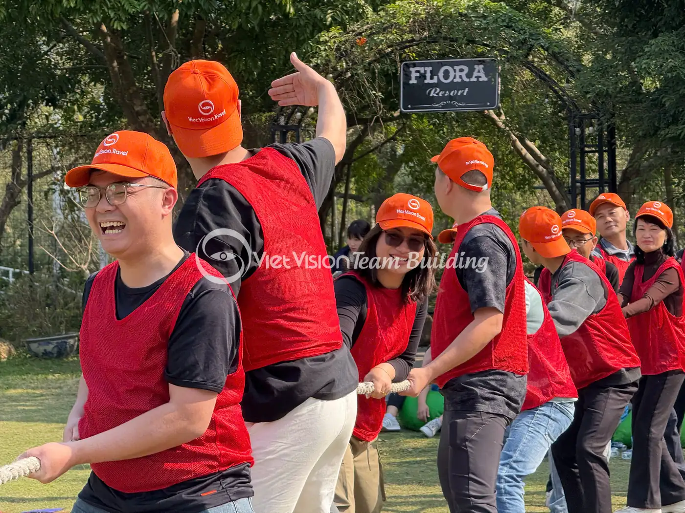 Đội chơi mặc áo đỏ và mũ cam xếp hàng trong một hoạt động team building