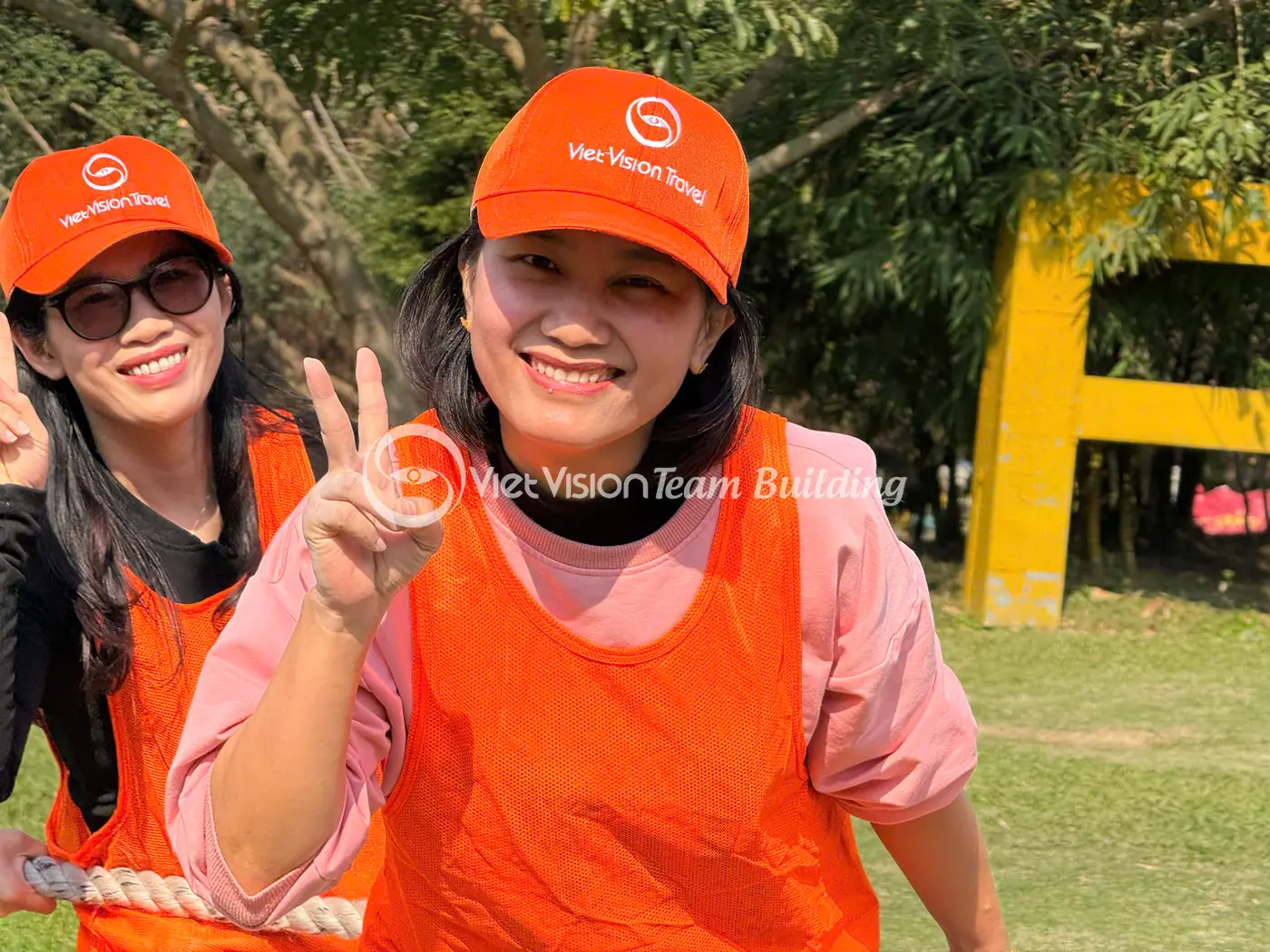 Hai người chơi mặc áo và mũ màu cam trong chương trình team building