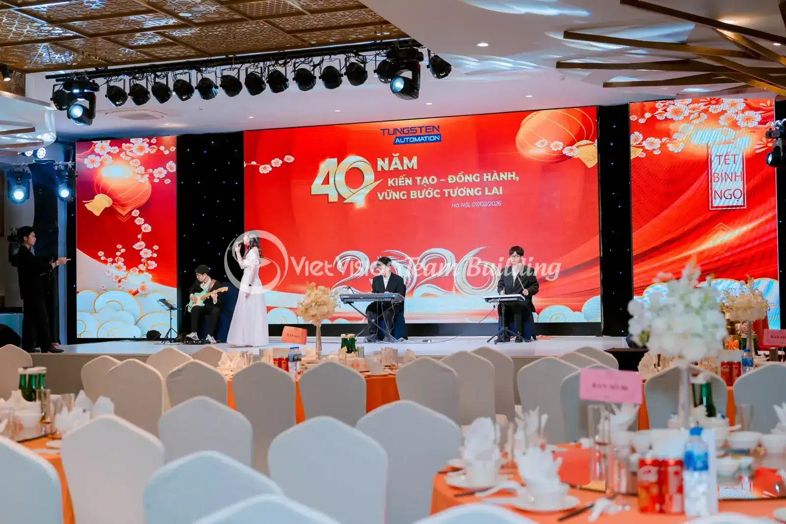 Các bàn tiệc được bố trí hướng về sân khấu trong sảnh doanh nghiệp